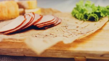 Fransız ekmeğiyle dilimlenmiş domuz filetosu. Sosis retro-stil yemek tepsisinde ve yemek kağıdında. Yavaş çekim kaydırağın üzerinde. Taze marul yaprakları da kullanıyoruz..