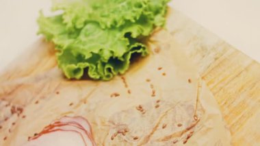 Fransız ekmeğiyle dilimlenmiş domuz pastırması. Sosis retro-stil yemek tepsisinde ve yemek kağıdında. Yavaş çekim kaydırağın üzerinde. Taze marul yaprakları da kullanıyoruz..