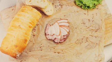 Fransız ekmeğiyle dilimlenmiş domuz pastırması. Sosis retro-stil yemek tepsisinde ve yemek kağıdında. Yavaş çekim kaydırağın üzerinde. Taze marul yaprakları da kullanıyoruz..