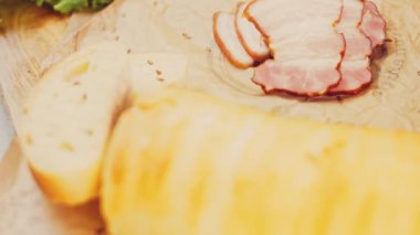 Fransız ekmeğiyle dilimlenmiş domuz pastırması. Sosis retro-stil yemek tepsisinde ve yemek kağıdında. Yavaş çekim kaydırağın üzerinde. Taze marul yaprakları da kullanıyoruz..