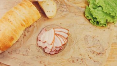 Fransız ekmeğiyle dilimlenmiş domuz pastırması. Sosis retro-stil yemek tepsisinde ve yemek kağıdında. Yavaş çekim kaydırağın üzerinde. Taze marul yaprakları da kullanıyoruz..