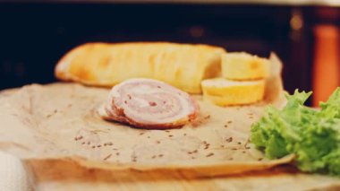 Fransız ekmeğiyle dilimlenmiş sosisli börek. Sosis retro-stil yemek tepsisinde ve yemek kağıdında. Yavaş çekim kaydırağın üzerinde. Taze marul yaprakları da kullanıyoruz..