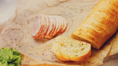Fransız ekmeğiyle dilimlenmiş sosisli börek. Sosis retro-stil yemek tepsisinde ve yemek kağıdında. Yavaş çekim kaydırağın üzerinde. Taze marul yaprakları da kullanıyoruz..