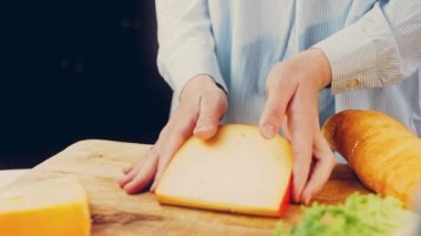 Kadın elinde delikli bir parça peynir tutuyor. Kaydırıcı peynir sunum sürecini kaydetti.