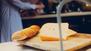 Retro-stil yemek tepsisinde delikleri olan peynir. Kaypak peynir sunum sürecini kaydetti. Arka planda Fransız ekmeği ve taze marul yaprakları var..