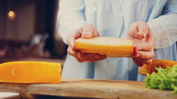 女性は手に穴のあるチーズを持っている スライダーはチーズのプレゼンテーションプロセスを撮影 — ストック動画