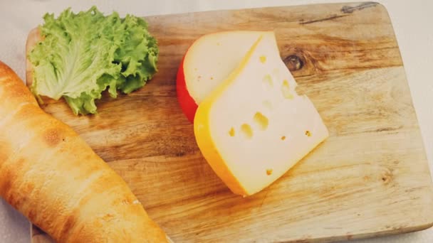 レトロスタイルの調理トレイに穴のあるチーズ スライダーはチーズのプレゼンテーションプロセスを撮影した 背景にはフランス風のバゲットとフレッシュなレタスの葉 — ストック動画