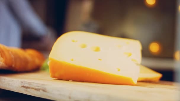 レトロスタイルの調理トレイに穴のあるチーズ スライダーはチーズのプレゼンテーションプロセスを撮影した 背景にはフランス風のバゲットとフレッシュなレタスの葉 — ストック動画