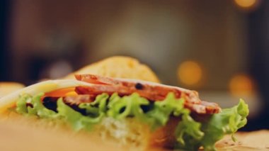 Fransız ekmeği, peynir, marul ve sosisli sandviç. Kaydırma atışı. Arka planda eski bir fırın tepsisi ve yemek kağıdı var..