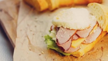 Şef kızarmış yumurtanın üzerine Fransız ekmeği, peynir, marul ve sosisle birlikte sanvich 'i buharla kaplayan bir kalp şeklinde parmesan serpiyor. Yumurta sarısı sandviçin üzerinden akıyor..