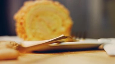 Kadın, altın çatallı fıstıkla sarılmış bir parça kek alıyor. Arka planda retro-stil yemek tepsisi üzerinde soyulmuş fıstık var. Makro ve sürgülü atış.