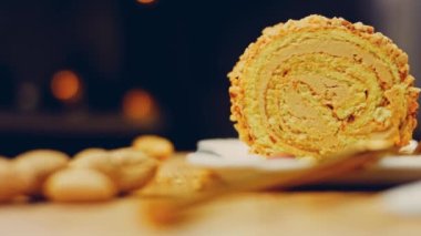 Kadın, altın çatallı fıstıkla sarılmış bir parça kek alıyor. Arka planda retro-stil yemek tepsisi üzerinde soyulmuş fıstık var. Makro ve sürgülü atış.