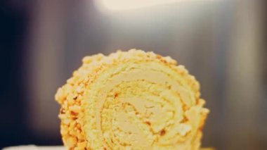 Kadın, altın çatallı fıstıkla sarılmış bir parça kek alıyor. Arka planda retro-stil yemek tepsisi üzerinde soyulmuş fıstık var. Makro ve sürgülü atış.