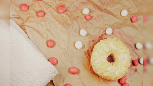 Розовые Пончики Украшенные Желтой Глазурью Пончики Клочке Бумаги Украшенном Конфетами — стоковое видео