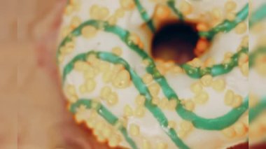 Mavi kremayla süslenmiş sarı çörekler. Çörekler şekerle süslenmiş bir kağıt parçasının üzerinde. Makro ve kaydırma atışı. Makro ve kaydırma atışı. Şekerler ağır çekimde hareket ediyor. Fırın ve yemek.