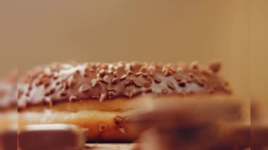 Çikolatalı çörekler çikolata parçalarıyla süslenmiş. Donutlar doğal çikolatayla süslenmiş bir kağıdın üzerinde. Makro ve kaydırma atışı. Fırın ve yemek konsepti. Çeşitli renkli çörekler. Çikolata, pembe