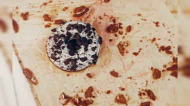 Oeo bisküvileriyle süslenmiş çikolatalı çörekler. Donutlar doğal çikolatayla süslenmiş bir kağıdın üzerinde. Makro ve kaydırma atışı. Fırın ve yemek konsepti. Çeşitli renkli çörekler. Çikolata.