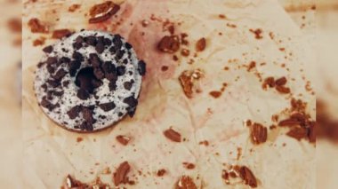 Oeo bisküvileriyle süslenmiş çikolatalı çörekler. Donutlar doğal çikolatayla süslenmiş bir kağıdın üzerinde. Makro ve kaydırma atışı. Fırın ve yemek konsepti. Çeşitli renkli çörekler. Çikolata.