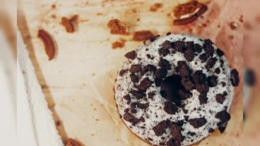 Oeo bisküvileriyle süslenmiş çikolatalı çörekler. Donutlar doğal çikolatayla süslenmiş bir kağıdın üzerinde. Makro ve kaydırma atışı. Fırın ve yemek konsepti. Çeşitli renkli çörekler. Çikolata.