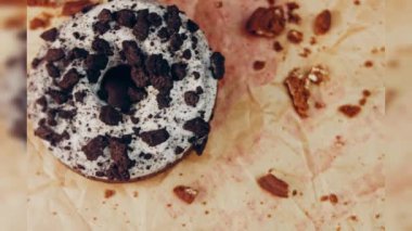 Oeo bisküvileriyle süslenmiş çikolatalı çörekler. Donutlar doğal çikolatayla süslenmiş bir kağıdın üzerinde. Makro ve kaydırma atışı. Fırın ve yemek konsepti. Çeşitli renkli çörekler. Çikolata.