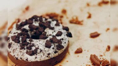 Oeo bisküvileriyle süslenmiş çikolatalı çörekler. Donutlar doğal çikolatayla süslenmiş bir kağıdın üzerinde. Makro ve kaydırma atışı. Fırın ve yemek konsepti. Çeşitli renkli çörekler. Çikolata.