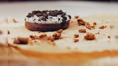 Oeo bisküvileriyle süslenmiş çikolatalı çörekler. Donutlar doğal çikolatayla süslenmiş bir kağıdın üzerinde. Makro ve kaydırma atışı. Fırın ve yemek konsepti. Çeşitli renkli çörekler. Çikolata.