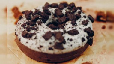 Oeo bisküvileriyle süslenmiş çikolatalı çörekler. Donutlar doğal çikolatayla süslenmiş bir kağıdın üzerinde. Makro ve kaydırma atışı. Fırın ve yemek konsepti. Çeşitli renkli çörekler. Çikolata.