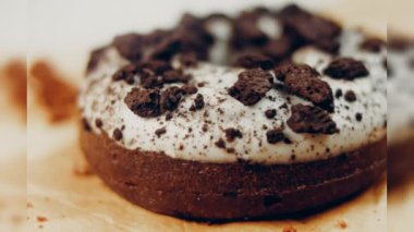 Oeo bisküvileriyle süslenmiş çikolatalı çörekler. Donutlar doğal çikolatayla süslenmiş bir kağıdın üzerinde. Makro ve kaydırma atışı. Fırın ve yemek konsepti. Çeşitli renkli çörekler. Çikolata.