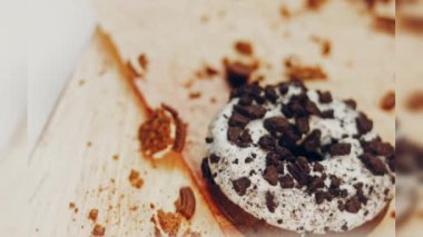 Oeo bisküvileriyle süslenmiş çikolatalı çörekler. Donutlar doğal çikolatayla süslenmiş bir kağıdın üzerinde. Makro ve kaydırma atışı. Fırın ve yemek konsepti. Çeşitli renkli çörekler. Çikolata.