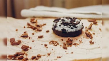 Oeo bisküvileriyle süslenmiş çikolatalı çörekler. Donutlar doğal çikolatayla süslenmiş bir kağıdın üzerinde. Makro ve kaydırma atışı. Fırın ve yemek konsepti. Çeşitli renkli çörekler. Çikolata.