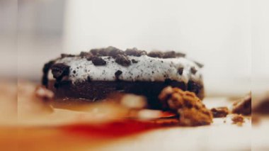 Oeo bisküvileriyle süslenmiş çikolatalı çörekler. Donutlar doğal çikolatayla süslenmiş bir kağıdın üzerinde. Makro ve kaydırma atışı. Fırın ve yemek konsepti. Çeşitli renkli çörekler. Çikolata.