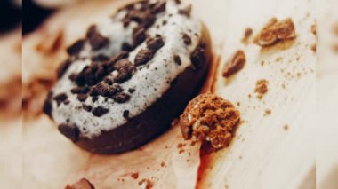 Oeo bisküvileriyle süslenmiş çikolatalı çörekler. Donutlar doğal çikolatayla süslenmiş bir kağıdın üzerinde. Makro ve kaydırma atışı. Fırın ve yemek konsepti. Çeşitli renkli çörekler. Çikolata.