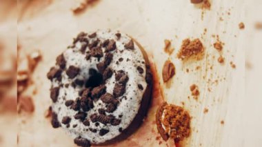 Oeo bisküvileriyle süslenmiş çikolatalı çörekler. Donutlar doğal çikolatayla süslenmiş bir kağıdın üzerinde. Makro ve kaydırma atışı. Fırın ve yemek konsepti. Çeşitli renkli çörekler. Çikolata.