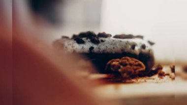 Oeo bisküvileriyle süslenmiş çikolatalı çörekler. Donutlar doğal çikolatayla süslenmiş bir kağıdın üzerinde. Makro ve kaydırma atışı. Fırın ve yemek konsepti. Çeşitli renkli çörekler. Çikolata.