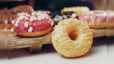 Çikolata, marşmelov ve retro pişirme tepsisindeki şekerli çörekler. Donutlar doğal çikolatayla süslenmiş bir kağıdın üzerinde. Makro ve kaydırma atışı. Çeşitli renkli çörekler. Çikolata, pembe, mavi çörekler
