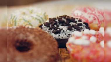 Çikolata, marşmelov ve retro pişirme tepsisindeki şekerli çörekler. Donutlar doğal çikolatayla süslenmiş bir kağıdın üzerinde. Makro ve kaydırma atışı. Çeşitli renkli çörekler. Çikolata, pembe, mavi çörekler