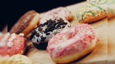 Çikolata, marşmelov ve retro pişirme tepsisindeki şekerli çörekler. Donutlar doğal çikolatayla süslenmiş bir kağıdın üzerinde. Makro ve kaydırma atışı. Çeşitli renkli çörekler. Çikolata, pembe, mavi çörekler