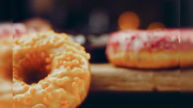 Çikolata, marşmelov ve retro pişirme tepsisindeki şekerli çörekler. Donutlar doğal çikolatayla süslenmiş bir kağıdın üzerinde. Makro ve kaydırma atışı. Çeşitli renkli çörekler. Çikolata, pembe, mavi çörekler