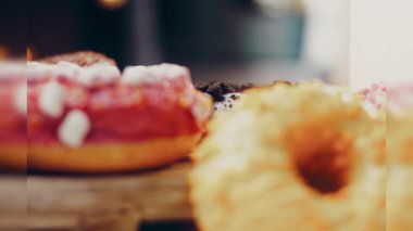 Çikolata, marşmelov ve retro pişirme tepsisindeki şekerli çörekler. Donutlar doğal çikolatayla süslenmiş bir kağıdın üzerinde. Makro ve kaydırma atışı. Çeşitli renkli çörekler. Çikolata, pembe, mavi çörekler