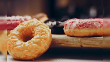 Çikolata, marşmelov ve retro pişirme tepsisindeki şekerli çörekler. Donutlar doğal çikolatayla süslenmiş bir kağıdın üzerinde. Makro ve kaydırma atışı. Çeşitli renkli çörekler. Çikolata, pembe, mavi çörekler