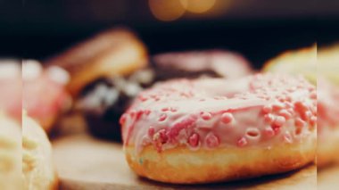 Çikolata, marşmelov ve retro pişirme tepsisindeki şekerli çörekler. Donutlar doğal çikolatayla süslenmiş bir kağıdın üzerinde. Makro ve kaydırma atışı. Çeşitli renkli çörekler. Çikolata, pembe, mavi çörekler