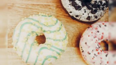 Çikolata, marşmelov ve retro pişirme tepsisindeki şekerli çörekler. Donutlar doğal çikolatayla süslenmiş bir kağıdın üzerinde. Makro ve kaydırma atışı. Çeşitli renkli çörekler. Çikolata, pembe, mavi çörekler