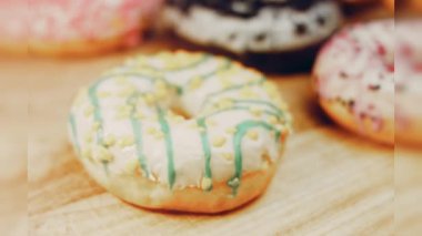 Çikolata, marşmelov ve retro pişirme tepsisindeki şekerli çörekler. Donutlar doğal çikolatayla süslenmiş bir kağıdın üzerinde. Makro ve kaydırma atışı. Çeşitli renkli çörekler. Çikolata, pembe, mavi çörekler