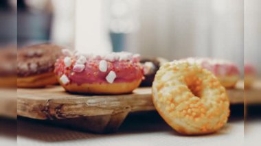 Çikolata, marşmelov ve retro pişirme tepsisindeki şekerli çörekler. Donutlar doğal çikolatayla süslenmiş bir kağıdın üzerinde. Makro ve kaydırma atışı. Çeşitli renkli çörekler. Çikolata, pembe, mavi çörekler