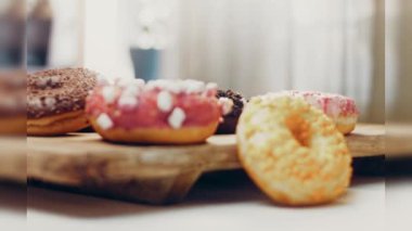 Çikolata, marşmelov ve retro pişirme tepsisindeki şekerli çörekler. Donutlar doğal çikolatayla süslenmiş bir kağıdın üzerinde. Makro ve kaydırma atışı. Çeşitli renkli çörekler. Çikolata, pembe, mavi çörekler