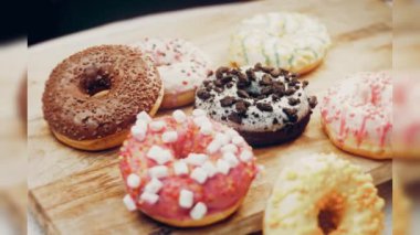 Çikolata, marşmelov ve retro pişirme tepsisindeki şekerli çörekler. Donutlar doğal çikolatayla süslenmiş bir kağıdın üzerinde. Makro ve kaydırma atışı. Çeşitli renkli çörekler. Çikolata, pembe, mavi çörekler