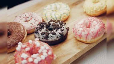 Çikolata, marşmelov ve retro pişirme tepsisindeki şekerli çörekler. Donutlar doğal çikolatayla süslenmiş bir kağıdın üzerinde. Makro ve kaydırma atışı. Çeşitli renkli çörekler. Çikolata, pembe, mavi çörekler