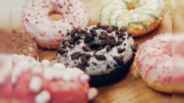 Çikolata, marşmelov ve retro pişirme tepsisindeki şekerli çörekler. Donutlar doğal çikolatayla süslenmiş bir kağıdın üzerinde. Makro ve kaydırma atışı. Çeşitli renkli çörekler. Çikolata, pembe, mavi çörekler