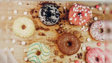 Çikolata, marşmelov ve retro pişirme tepsisindeki şekerli çörekler. Donutlar doğal çikolatayla süslenmiş bir kağıdın üzerinde. Makro ve kaydırma atışı. Çeşitli renkli çörekler. Çikolata, pembe, mavi çörekler