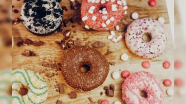 Çikolata, marşmelov ve retro pişirme tepsisindeki şekerli çörekler. Donutlar doğal çikolatayla süslenmiş bir kağıdın üzerinde. Makro ve kaydırma atışı. Çeşitli renkli çörekler. Çikolata, pembe, mavi çörekler